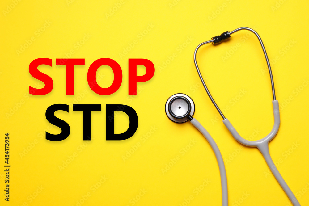 Text STOP STD and stethoscope on yellow background, top view Text STOP STD and stethoscope on yellow background, top view