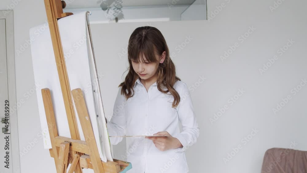 Child Painting on Easel, School Kid in Workshop Class. Young Girl Working Art Craft in Classroom Child Painting on Easel, School Kid in Workshop Class. Young Girl Working Art Craft in Classroom