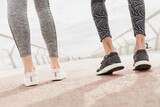 Close up cropped shot of sportive shoes trainers footwear. Man and woman athletes jogging running together on city bridge in the morning