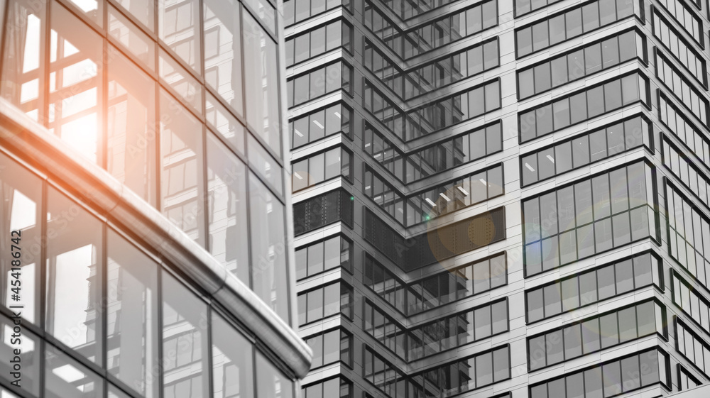 Modern architectural details. Modern glass facade with a geometric pattern. Contemporary corporate business architecture. Red sun on horizon. Black and white toned image. Modern architectural details. Modern glass facade with a geometric pattern. Contemporary corporate business architecture. Red sun on horizon. Black and white toned image.