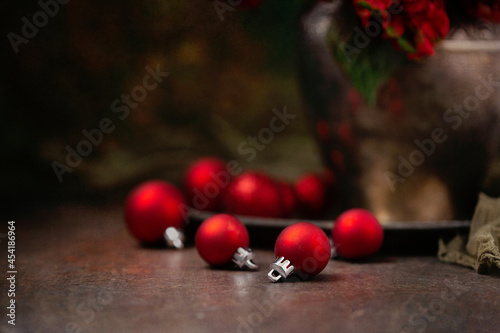 Red Christmas Ornaments on a Wood Table with a Silver Vase of Red Hydrangeas in the Background