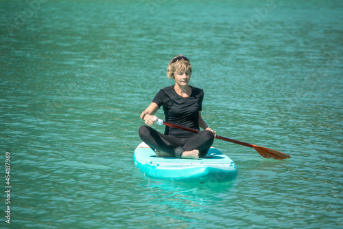 SUP concept surfboard - cute young woman is paddling on a beautiful lake with turquoise water