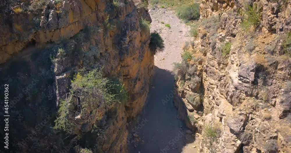 Video of a drone flying over shallow gorge and canyon in a dry desert area. Rugged terrain and geology erosion concept Video of a drone flying over shallow gorge and canyon in a dry desert area. Rugged terrain and geology erosion concept