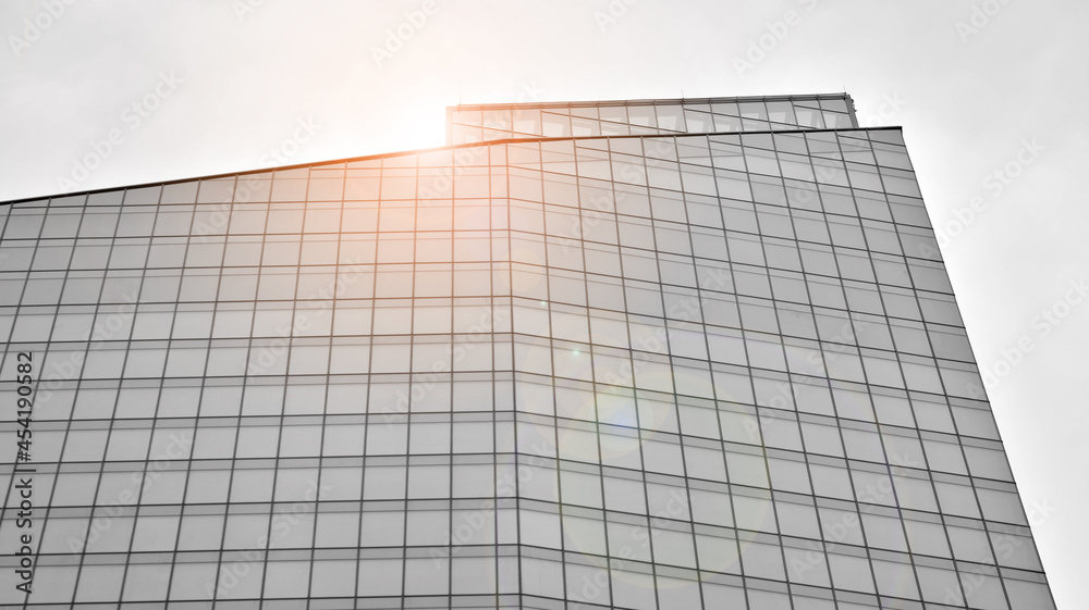 Modern architectural details. Modern glass facade with a geometric pattern. Contemporary corporate business architecture. Red sun on horizon. Black and white toned image. Modern architectural details. Modern glass facade with a geometric pattern. Contemporary corporate business architecture. Red sun on horizon. Black and white toned image.