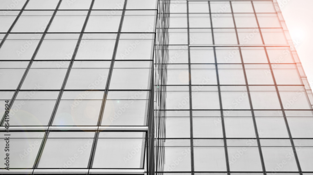 Modern architectural details. Modern glass facade with a geometric pattern. Contemporary corporate business architecture. Red sun on horizon. Black and white toned image. Modern architectural details. Modern glass facade with a geometric pattern. Contemporary corporate business architecture. Red sun on horizon. Black and white toned image.