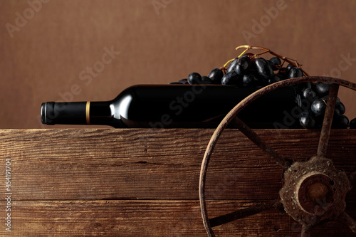 Old wooden cart with bottle of red wine and grapes.