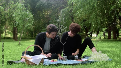 Two young guys in love listen to music in nature in the summer
