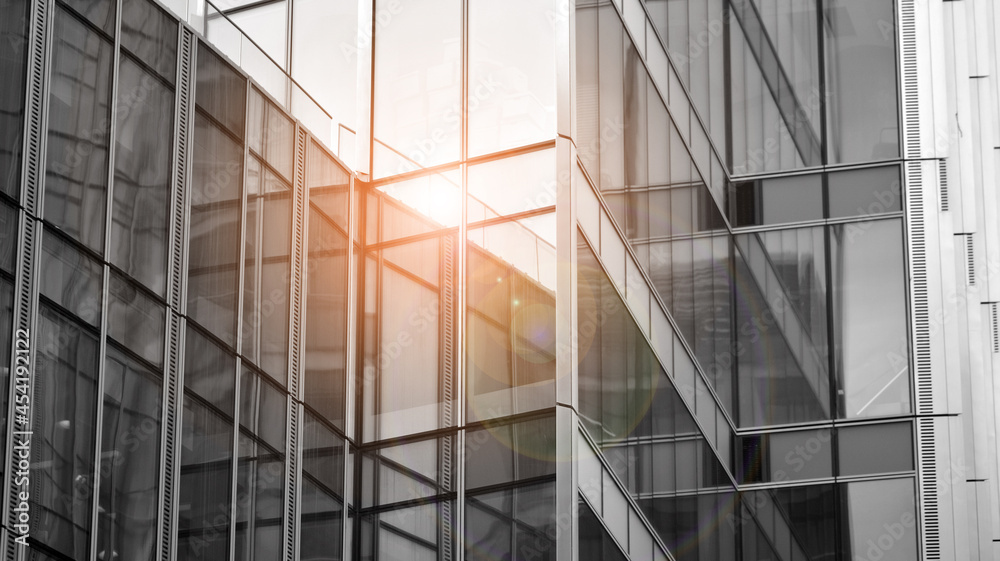 Modern architectural details. Modern glass facade with a geometric pattern. Contemporary corporate business architecture. Red sun on horizon. Black and white toned image. Modern architectural details. Modern glass facade with a geometric pattern. Contemporary corporate business architecture. Red sun on horizon. Black and white toned image.