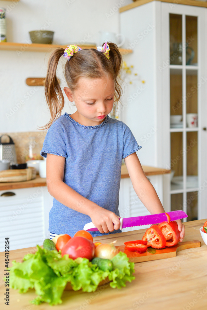 Adorable child is cooking in the kitchen. Pretty pretty girl prepares soup. Little chef preparing healthy food vegetable salad Adorable child is cooking in the kitchen. Pretty pretty girl prepares soup. Little chef preparing healthy food vegetable salad