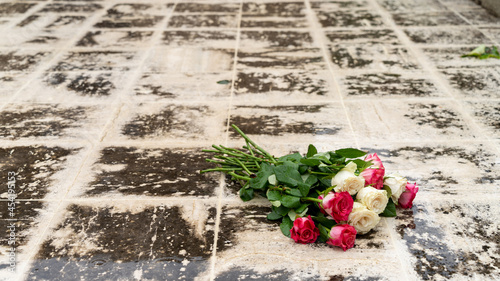 Close-up on a bouquet of roses, white and pink, on a paved outdoor floor, in rainy weather