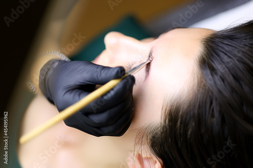 close-up of the master combs the eyebrows of the model with a brush after the procedure of long-term eyebrow styling