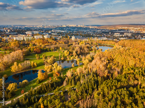 Aerial view of a lake in a park with autumn trees. Kishinev  Moldova. Epic aerial flight over water. Colorful autumn trees in the daytime.