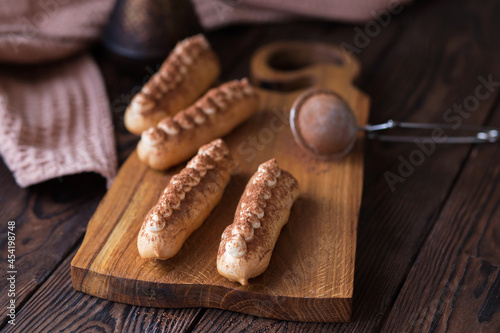 French dessert. Coffee eclairs on a brown background. Sweet French food. Home bakery. Eclair on a wooden board.