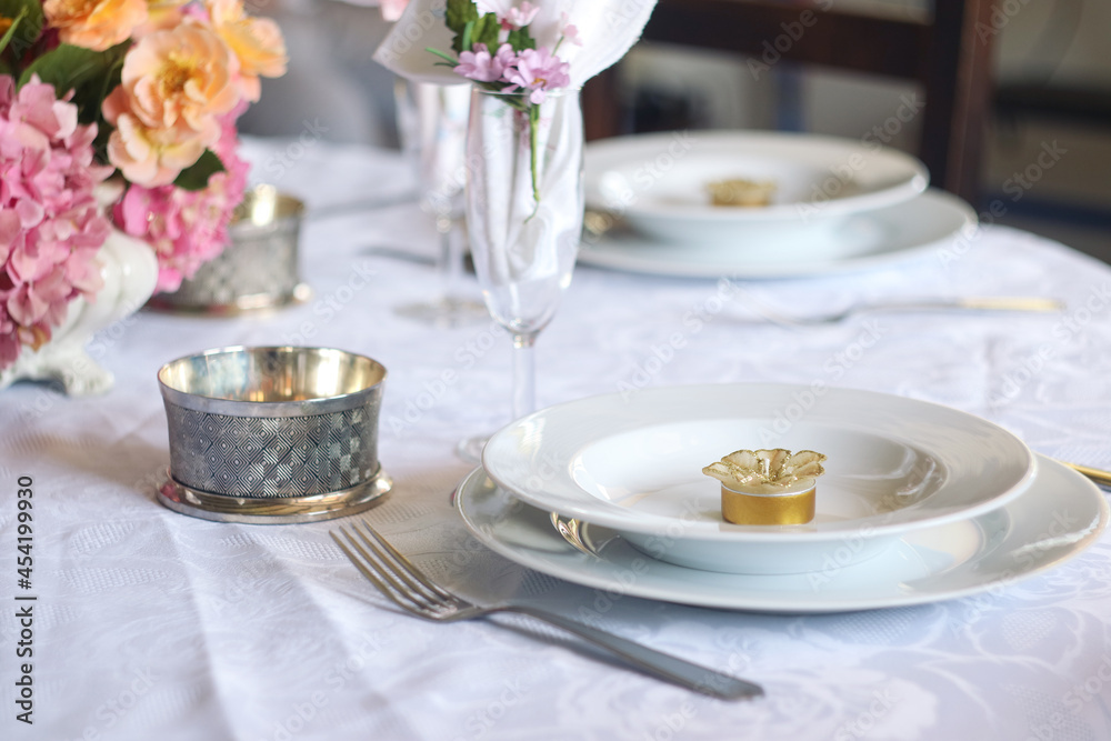 A table meal decoration with white plate and spoon, glasses of champagne and beautiful fresh flower with festive and celebrate atmosphere A table meal decoration with white plate and spoon, glasses of champagne and beautiful fresh flower with festive and celebrate atmosphere