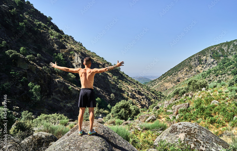 Young caucasian man with open arms in a nice landscape with mountains