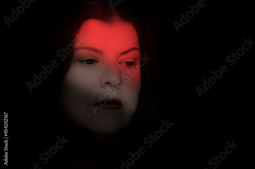 Adult lady with serious expression, looking down with light effect as part of the mood of the portrait © Alejandro
