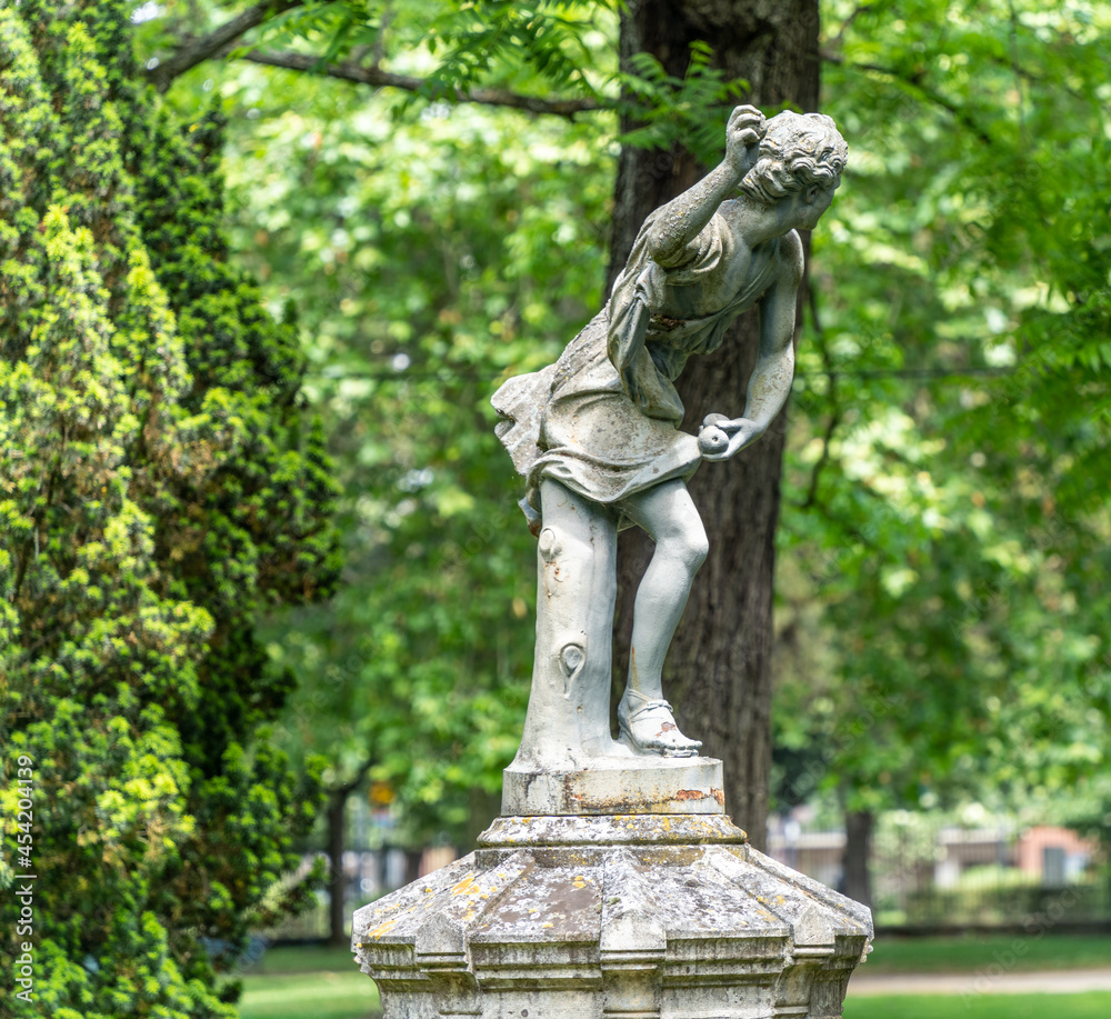 Magnificent statue of a leaning character throwing something, in the middle of lush green vegetation Magnificent statue of a leaning character throwing something, in the middle of lush green vegetation