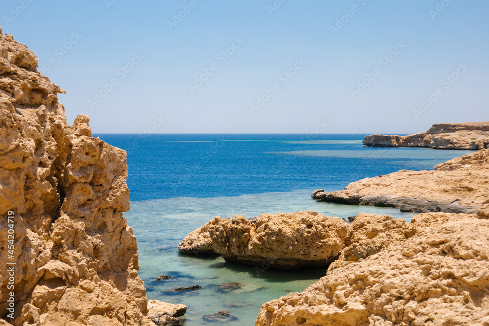 Sandy and rocky coast with blue color of water. Desolate beach on the coast shore of Red Sea. Ras Muhammad in Egypt at the southern extreme of the Sinai Peninsula. Travel concept