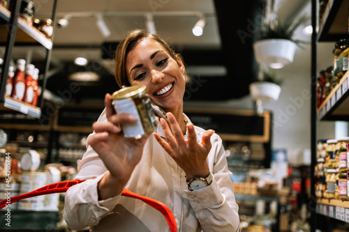 Beautiful young and elegant woman buying some healthy food and drink in modern supermarket or grocery store. Lifestyle and consumerism concept.