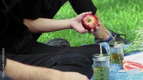 A guy gives an apple in the hand to another guy at a picnic in the summer