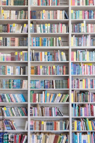 Blurred image of a library with bookcases. Many different books on the shelves. Large selection of books in a bookcase. Blurred background. photo