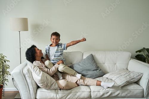 Black mother and her son resting on couch