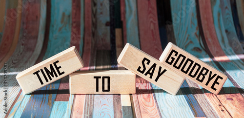 Text TIME TO SAY GOODBYE on wooden blocks and bright striped background