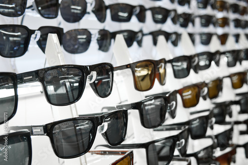 Lot of sunglasses on the counter of an optical store. Assortment of sunglasses.