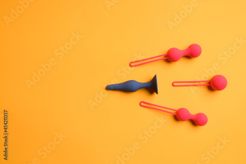 Anal black plug and three red balls, on a yellow background.sex shop