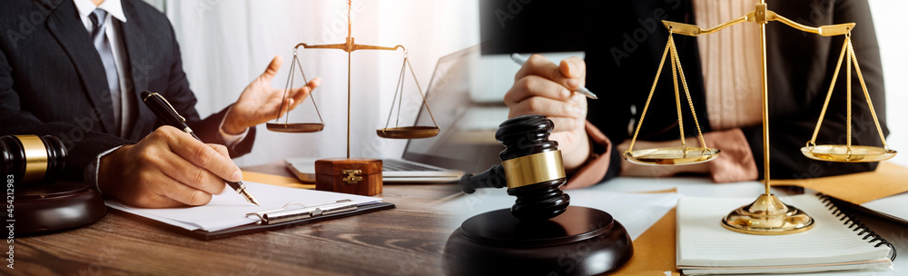 Justice and law concept.Male judge in a courtroom with the gavel, working with, computer and docking keyboard, eyeglasses, on table in morning light Justice and law concept.Male judge in a courtroom with the gavel, working with, computer and docking keyboard, eyeglasses, on table in morning light