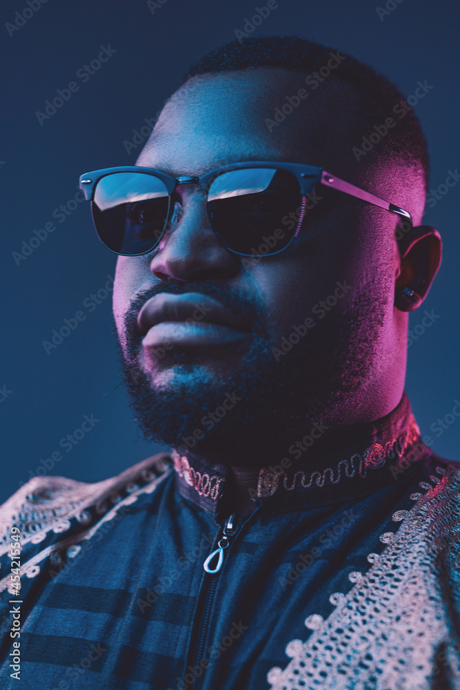 Obraz premium African fashion guy with sunglasses against dark background