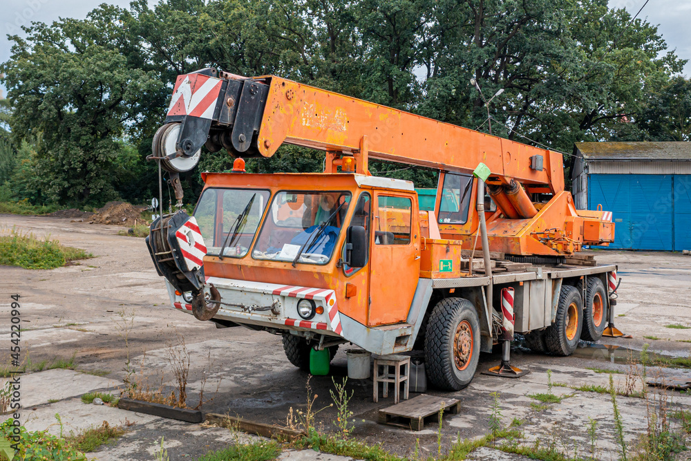 Old orange truck crane stands in the parking lot