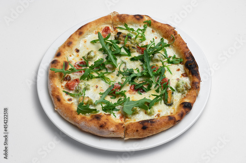 closeup of seafood pizza with shrimp, mussels and arugula on white background