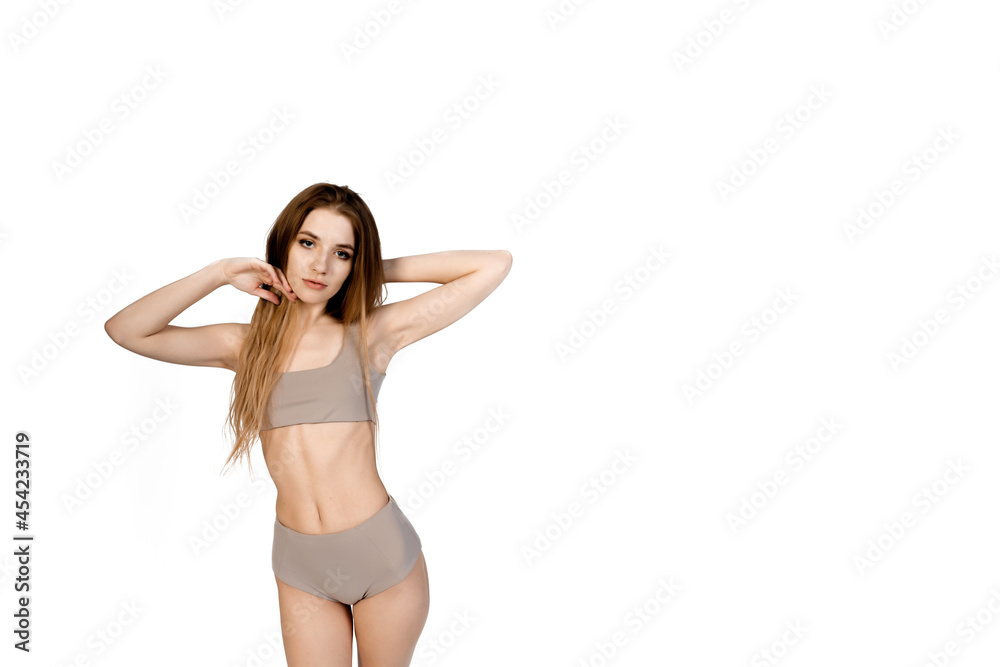 Young, fit and beautiful slender girl in gray sports underwear posing on a white background. Health care, diet, sport and fitness concept Young, fit and beautiful slender girl in gray sports underwear posing on a white background. Health care, diet, sport and fitness concept