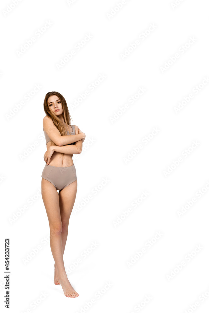 Young, fit and beautiful slender girl in gray sports underwear posing on a white background. Health care, diet, sport and fitness concept 