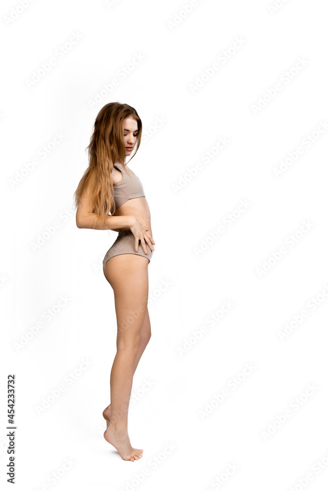Young, fit and beautiful slender girl in gray sports underwear posing on a white background. Health care, diet, sport and fitness concept Young, fit and beautiful slender girl in gray sports underwear posing on a white background. Health care, diet, sport and fitness concept