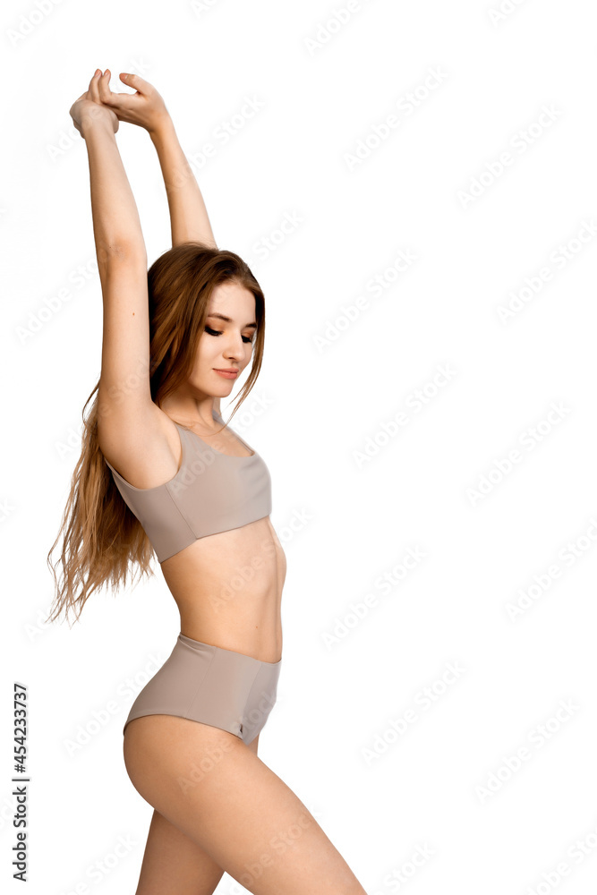 Young, fit and beautiful slender girl in gray sports underwear posing on a white background. Health care, diet, sport and fitness concept 