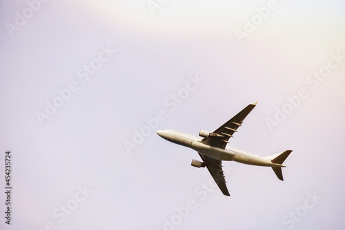 Passenger plane is flying far away against the blue summer and cloudy sky with copy space