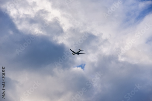 Passenger airplane is flying far away against the sky with clouds