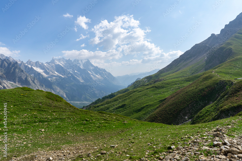 Fototapeta premium Panoramic view of relaxing mountain scenery with mountains in the background and meadow, grass, and rocks on a nice, sunny day