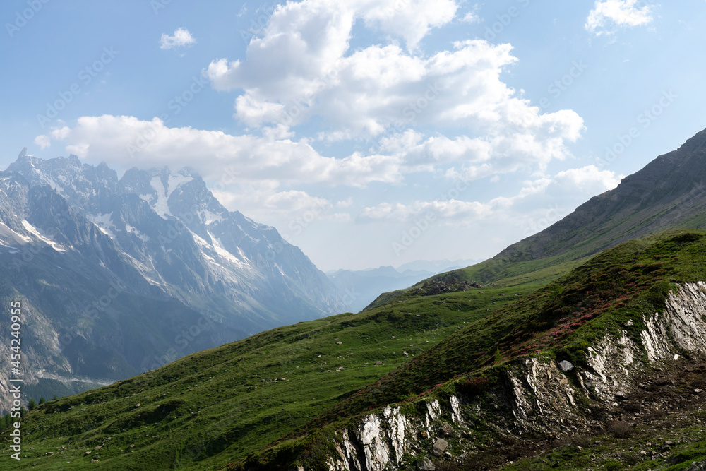 Fototapeta premium Panoramic view of relaxing mountain scenery with mountains in the background and meadow, grass, and rocks on a nice, sunny day