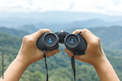 Hands holding binoculars on mountains background photo
