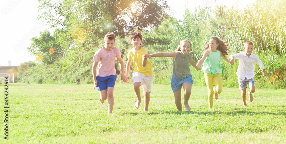 Fototapeta premium Happy active children running together on green grass in park