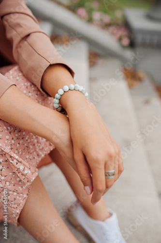 cute bracelet decoration on a woman s hand and a powdery delicate suit skirt and jacket  unrecognizable without a face. stylish trend jewelry. energy trappings. selective focus