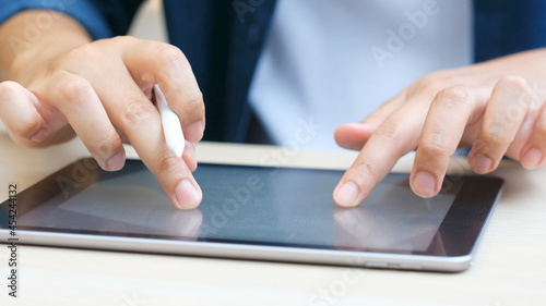 Close up of man hand writing on digital tablet while working at home, online study, telecommunication