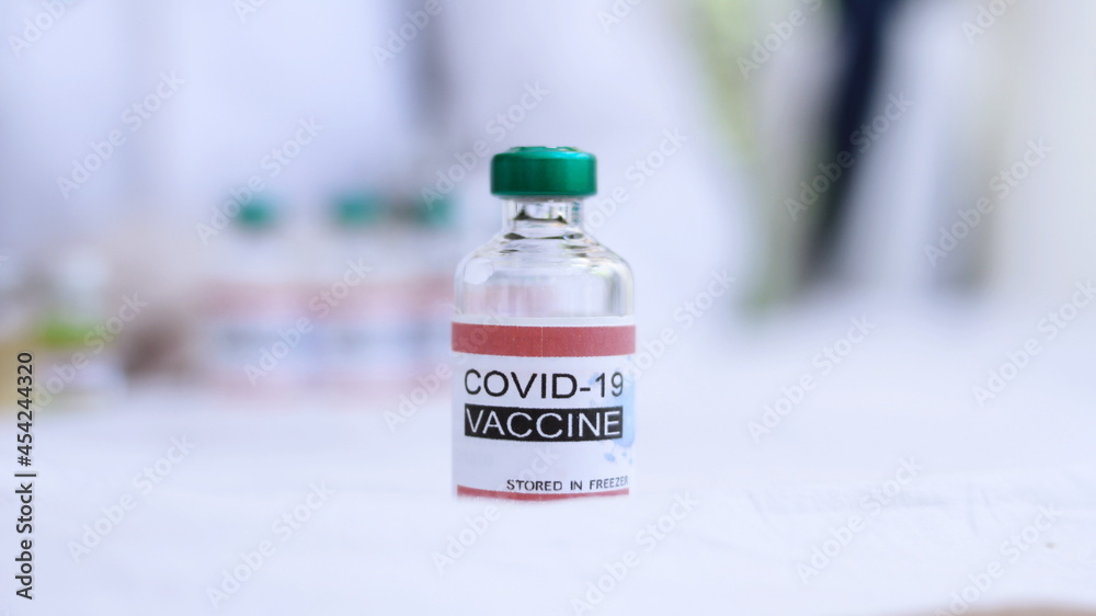 COVID-19 VACCINE, bottle of vaccine is placed on a doctor's desk in a hospital lab.