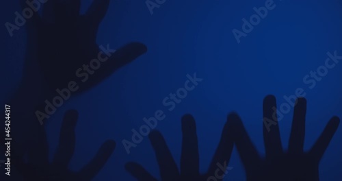 Silhouette of Creepy human hands moving on glass window