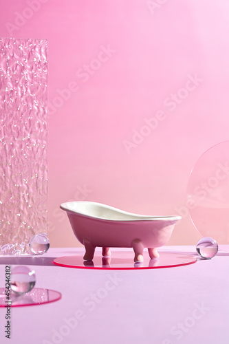 Bath tub mini with Glass Geometric podium and marbles . Monochrome platform with ribbed acrylic sheets and crystal podium on radiant pink background. Stylish background for presentation
