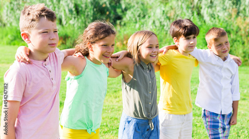 Portrait of five glad children who are walking and posing in the park