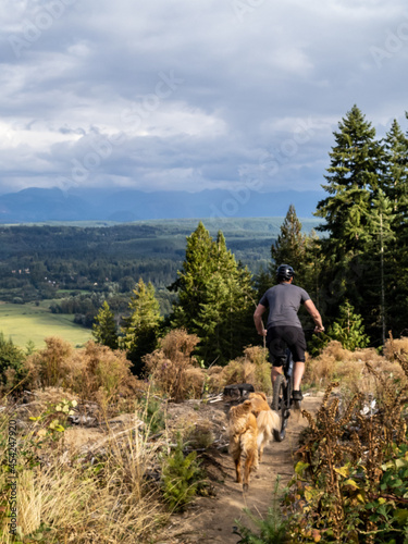 Man riding a mountain bike with his dogs.  photo